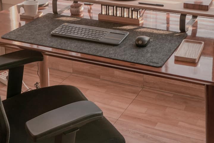 Escritorio de oficina con teclado, ratón y una silla con apoyabrazos.